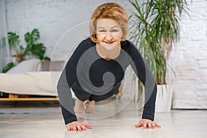 Mature woman doing push-UPS at home, healthy lifestyle concept