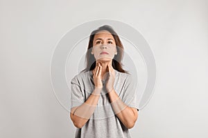 Mature woman doing thyroid self examination on light background