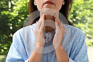 Mature woman doing thyroid self examination near window, closeup