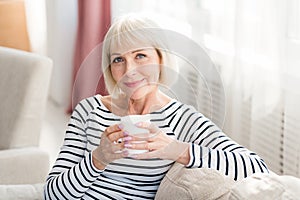 Mature woman drinking fresh morning coffee at home