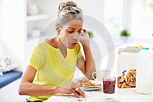 Mature Woman Eating Breakfast And Reading Newspaper