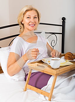 Mature woman enjoying breakfast in bed