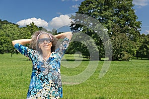 Mature woman enjoying the sun field trees Blue sky