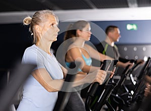 Mature woman exercising on an elliptical trainer in gym