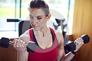 Mature Woman Exercising In Home Gym Lifting Hand Weights