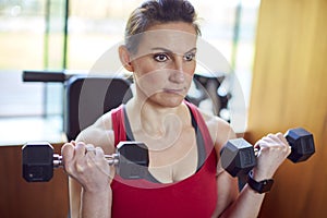 Mature Woman Exercising In Home Gym Lifting Hand Weights