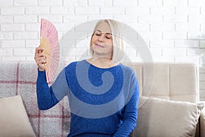 Mature woman experiencing hot flush from menopause. This photo captures the discomfort of hot flashes during menopause photo