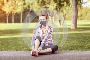 Mature woman with face mask tying sport shoes before running