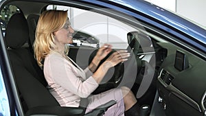 Mature woman fastening seatbelt sitting in a new car at the dealership