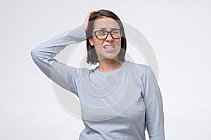 Mature woman with glasses scratching head, thinking daydreaming deeply about something