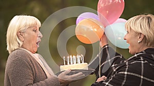 Mature woman going to blow out candles on birthday cake from best friend