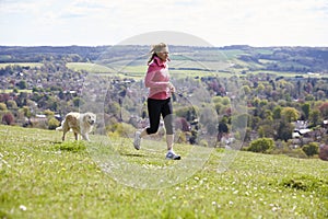 Mature Woman With Golden Retriever Jogging In Countryside