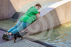 Mature woman in green shirt with small dog resting in the Park