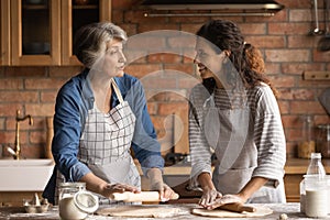 Mature woman with grownup daughter chatting, cooking homemade pastry