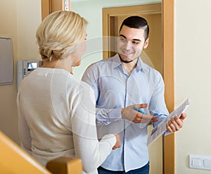 Mature woman and guy with papers at door