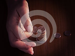Mature, woman hand putting coins into a pile, heap, on white tablecloth background. Close. European euro coins, counting photo
