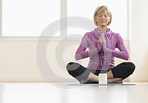 Mature Woman With Hands Clasped Meditating At Home