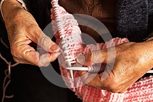 Mature woman hands knitting with knitting needles and pink wool