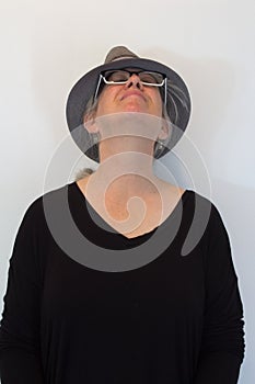 Mature woman in hat, head tilted back, eyes closed, neutral background