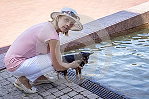 Mature woman in a hat with a small dog resting in the Park by the water