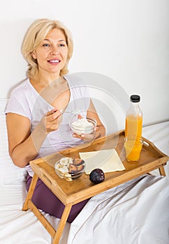 Mature woman having breakfast in bed