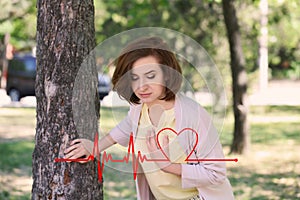 Mature woman having heart attack near tree