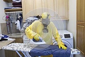 Mature woman in Haz Mat suit ironing shirt on board with steam photo