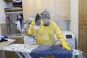 Mature woman in Haz Mat suit ironing shirt on board photo