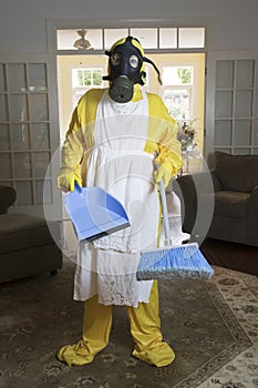 Mature woman in Haz Mat suit in living room with broom photo