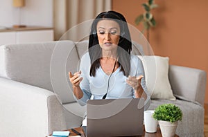 Mature woman in headset having video call on computer