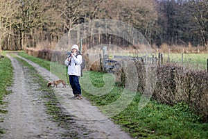 Mature woman with her gimbal mobile phone tripod head stabilizer filming in a nature reserve