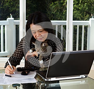 Mature woman and her pet cat working at home