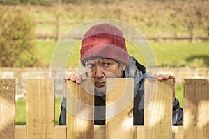 Mature woman hiding behind fence