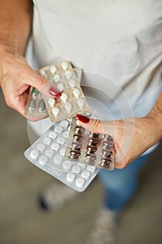 Mature woman hold in hand blister pack of pills