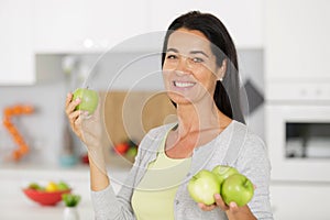 Mature woman holding apples at home