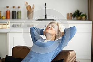 Mature woman holding hand behind head, resting at home