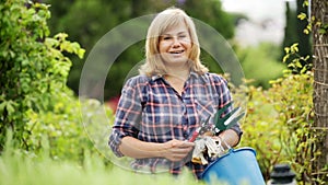 mature woman holding horticultural tools in garden