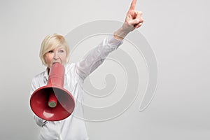 Mature woman is holding a megaphone close to her mouth and sreaming into it. She is defending human rights. on