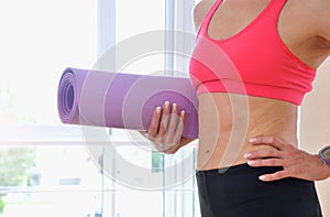 Mature woman holding rolled up exercise mat at gym