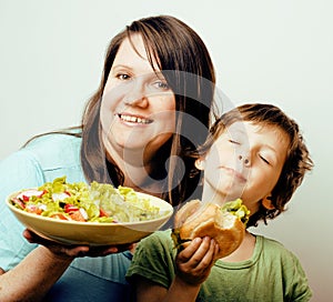 Mature woman holding salad and little cute boy with hamburger te