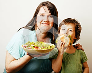 Mature woman holding salad and little cute boy with hamburger te