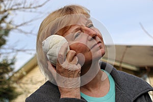 Mature woman holding seashell to ear