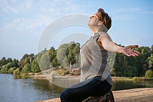 Mature woman at holiday destination beach contemplating lake sitting on shore