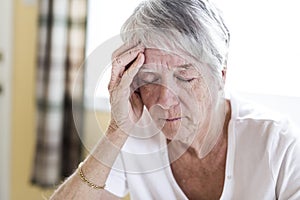 Mature woman at home touching her head with her hands while having a headache pain