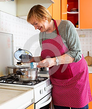 Mature woman housewife during cooking soup at her kitchen