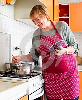 Mature woman housewife during cooking soup at her kitchen