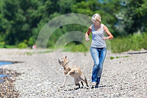 Mature woman jogs with a dog riverside