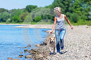 Mature woman jogs with a dog riverside