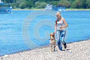 Mature woman jogs with a dog riverside