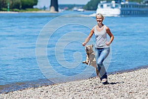 Mature woman jogs with a dog riverside